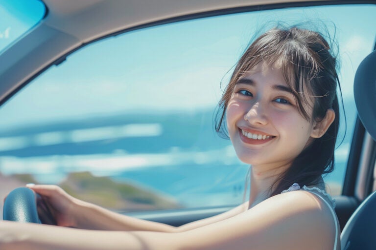夏のドライブでハンドルを握る若い女性のイメージ