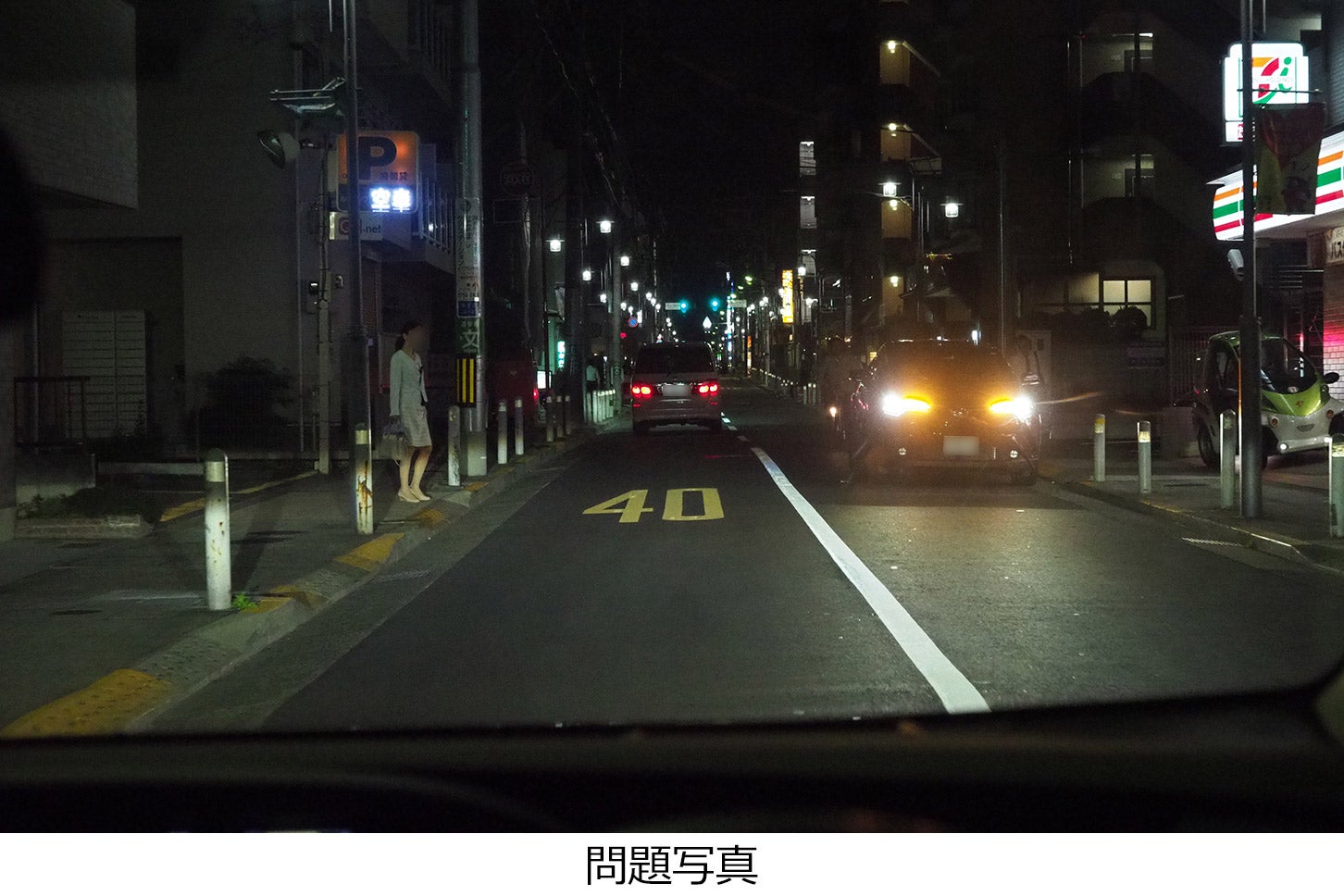 夜間、右側にコンビニがある道路で、停車車両の側方を通過しようとしています。