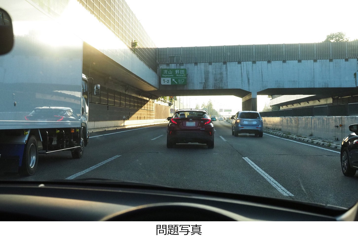片側3車線の高速道路の中央車線を走っています。日が落ち始め、交通量は多く車間は詰まり気味です。