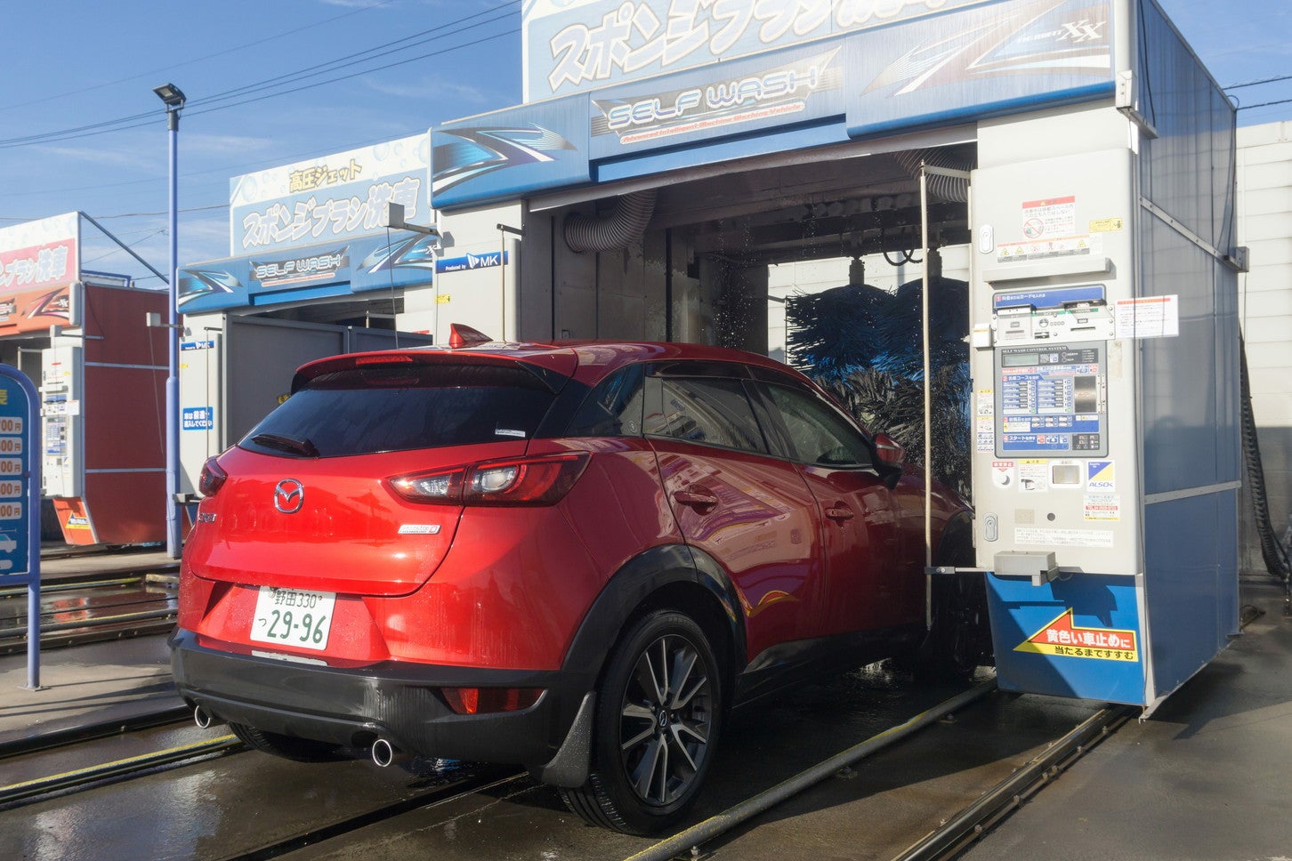 クルマを所定の位置に停めると、洗車機が前後して自動で洗浄してくれる。(c) xiaosan – stock.adobe.com