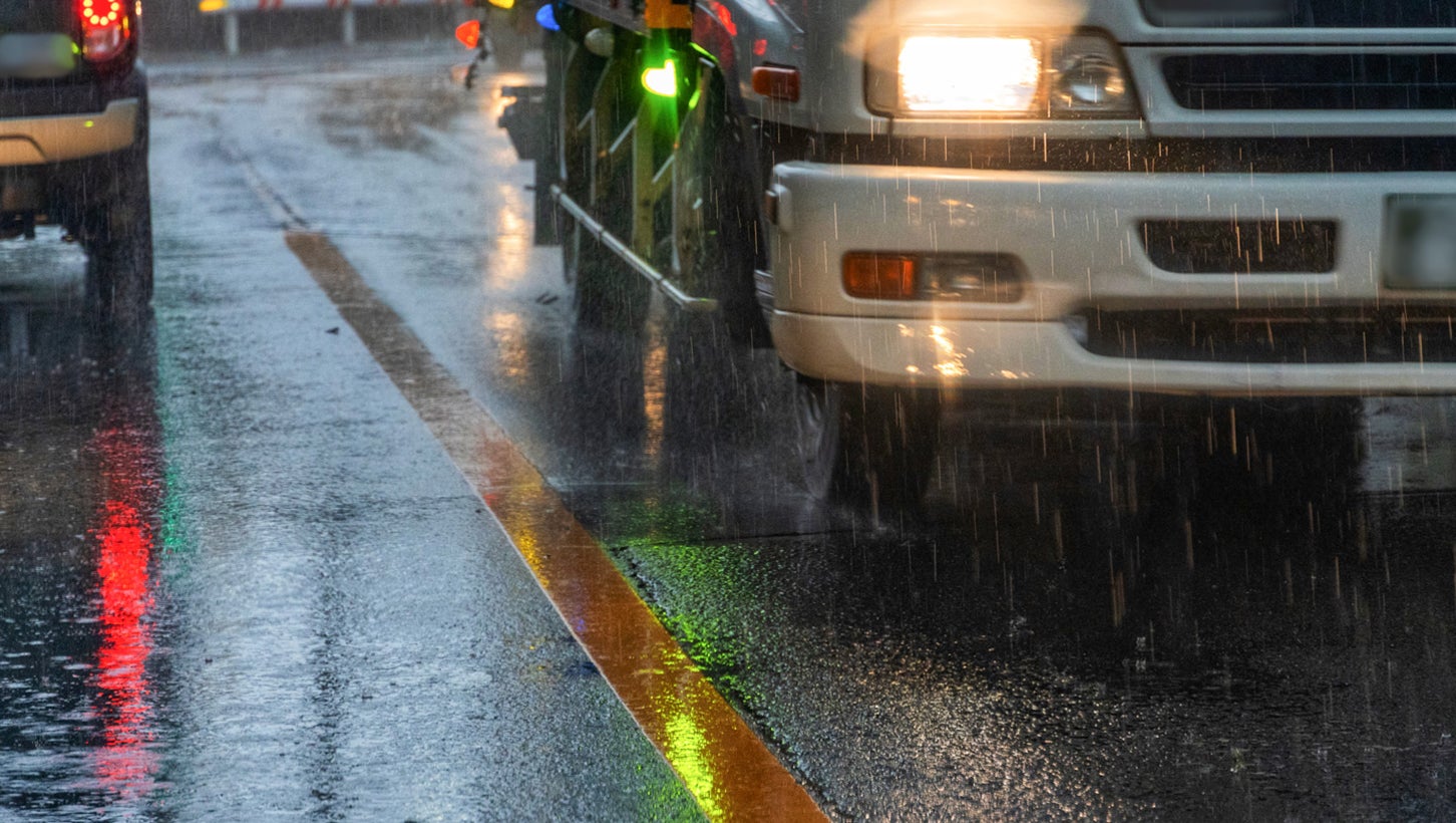 雨の日の夜の道路。濡れた路面が光って、区間線が見えにくくなる。画像:写真AC