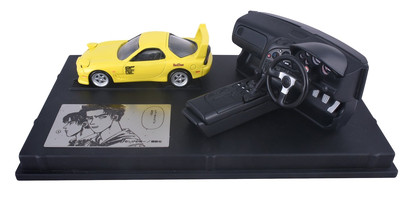 トミカプレミアム unlimited STEERING VIEW 頭文字D FD3S RX-7（第1巻仕様）。ダッシュボードには、改造されたブースト計やオーディオ機器、エアコンが配置されている。