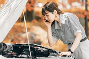クルマの点検をする女性。(c)Trickster – stock.adobe.com