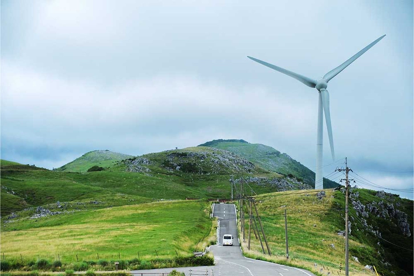 重なる丘を越えていこうとする白くま。右手には大きな風力発電機がそびえ立ちます