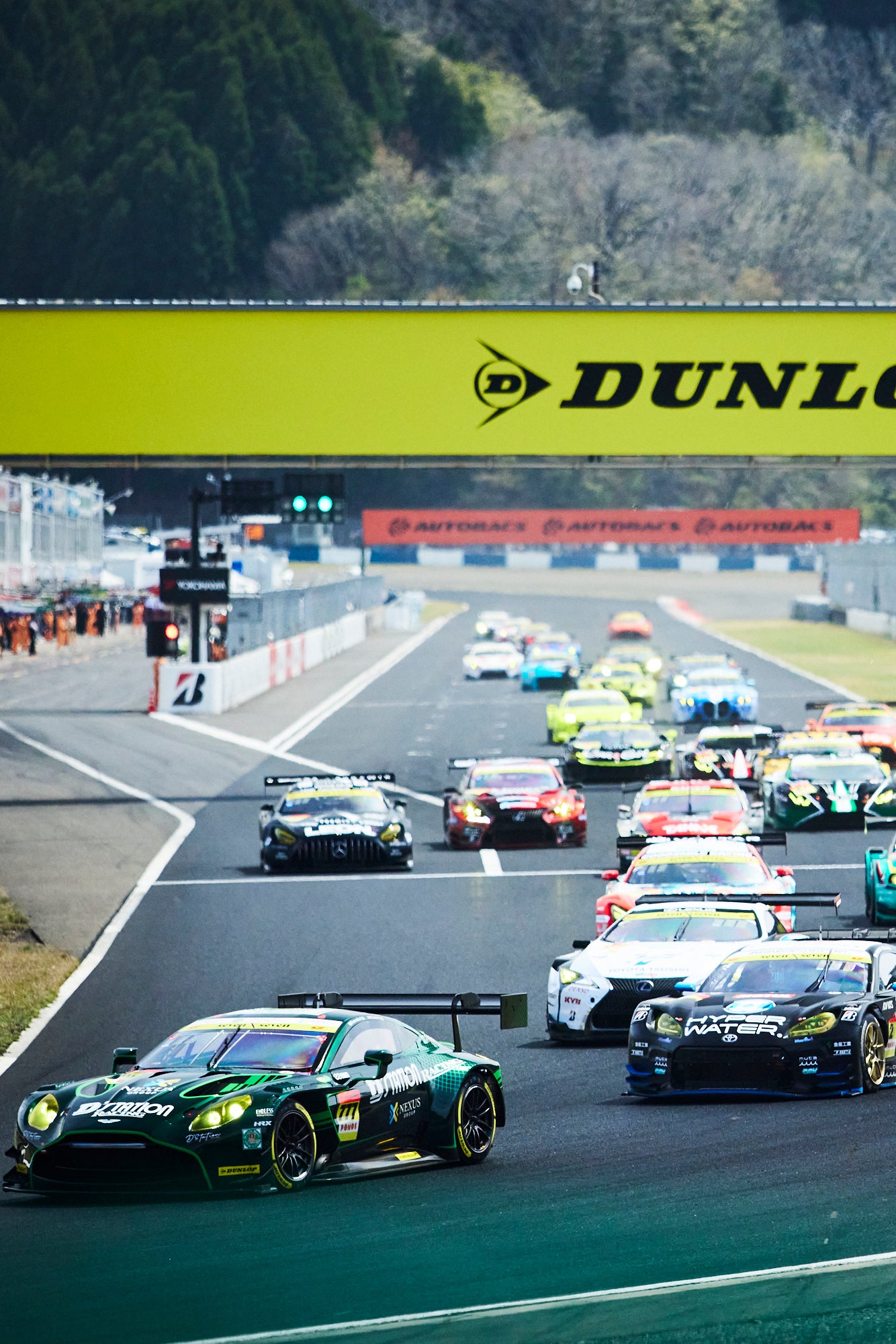 ローリングスタートから1コーナーへなだれ込むGT300クラスの29台の車両。3位表彰台を獲得する小山美姫がドライブする31号車、apr LC500h GTはこの時点ですでに3番手につけている。