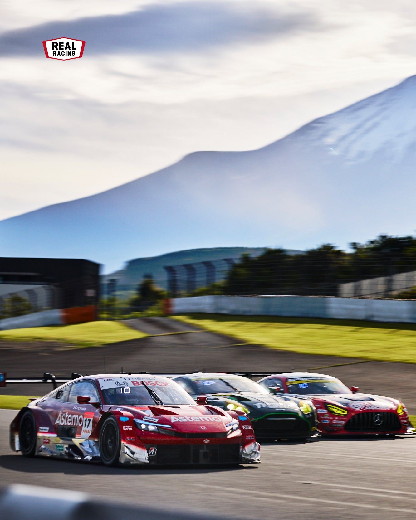 富士スピードウェイ！ を象徴する霊峰富士山とGTマシーンの3ワイド。この最終コーナーからこのサーキットの名物、全長1.5km弱のストレートがはじまる。