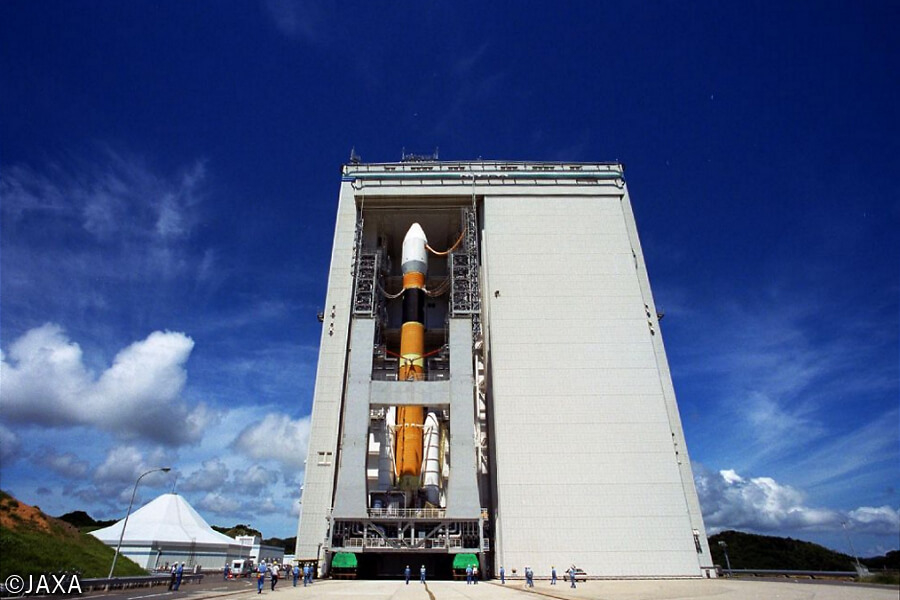 JAXA・種子島宇宙センターの大型ロケット組立棟の巨大な1枚スライドドアが開いて、ドーリーがH-IIAロケットとともに移動発射台を運搬してくるところ。