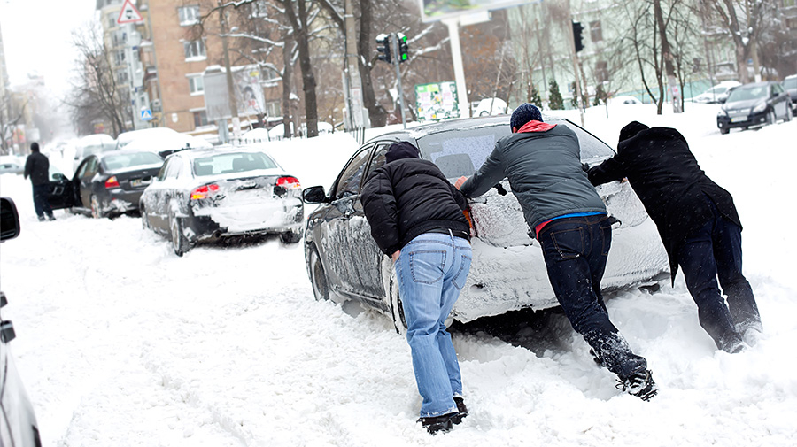 雪でスタックした車を押す人たち