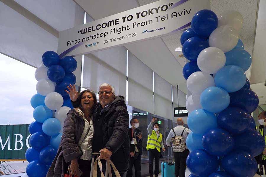 搭乗口で「ようこそ東京へ」と書かれたアーチを見つけ、記念写真を撮影する乗客