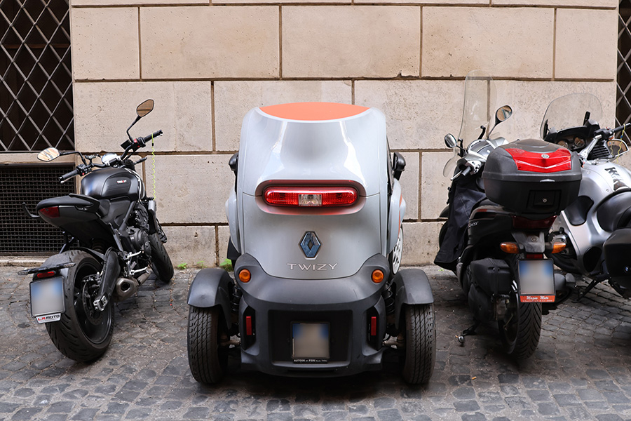 2輪と並んで駐車するルノー・トゥイジー。後部のナンバープレートは2輪規格だ。ローマで2023年2月。